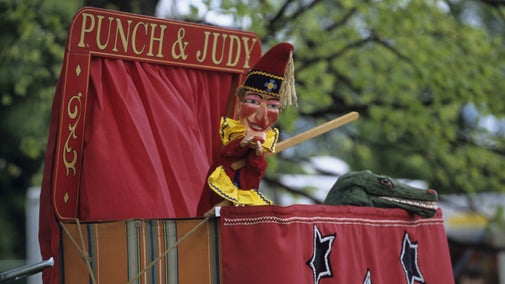 Punch the puppet in traditional costume with crocodile in a Punch and Judy puppet show.